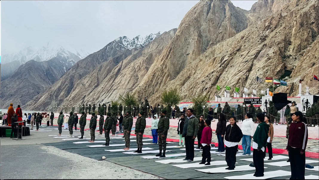 Rows of practitioners on mats in a high mountain valley, a rock face behind them